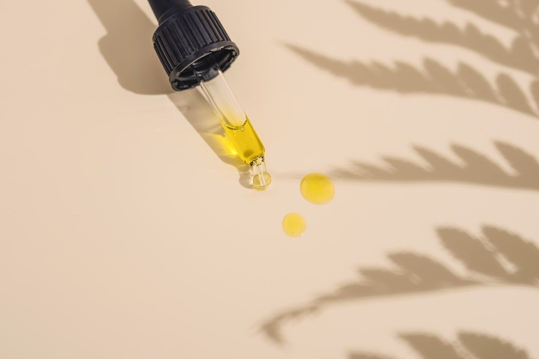 Dropper releasing yellow skincare serum onto a sunlit surface