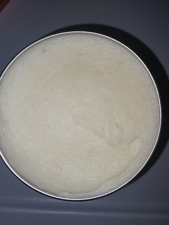 Open round tin filled with a pale, smooth anhydrous balm