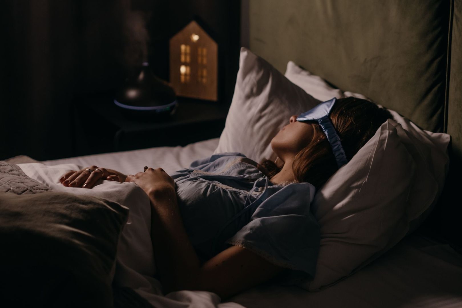 Woman sleeping in bed at night beside a softly glowing bedside device